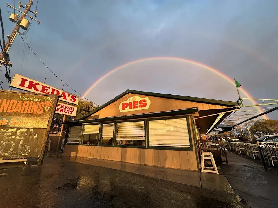 Ikeda's market building with its red PIES sign under a full rainbow after a rain