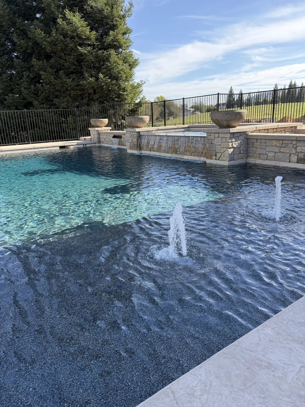 CJR pool with bubblers and a raised stone wall topped with planter bowls